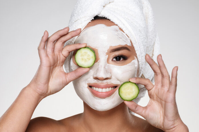 attractive-smiling-lady-with-scrab-face-holding-cucumber-slices